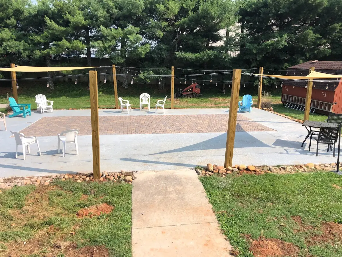 Patio with a brick paver center, outdoor chairs, and string lights