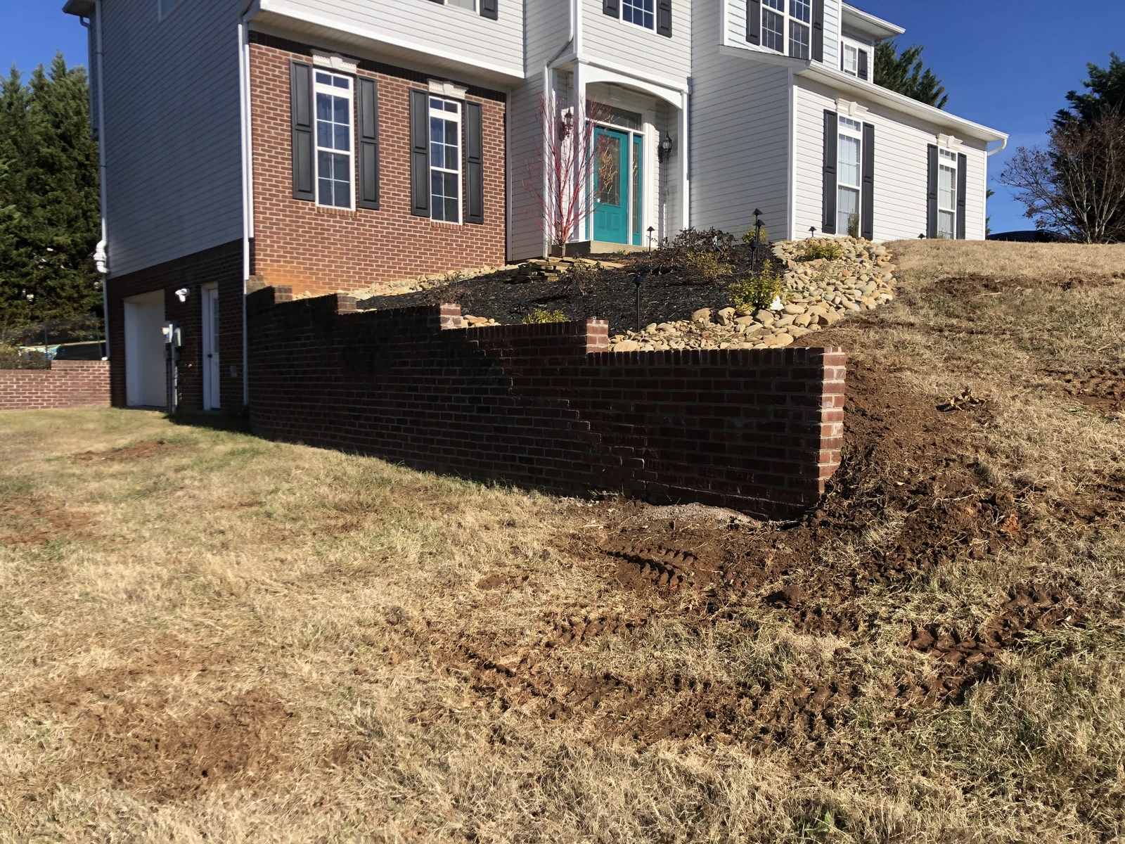 Raised landscape bed with a retaining wall beside a brick home